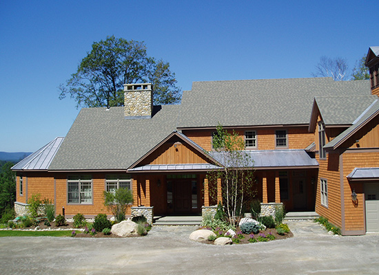 Picture of new wooden home with trees and shrub plantings in the front