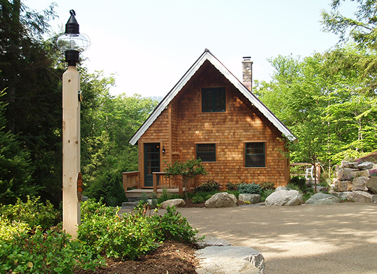 Picture of shingle home with large rocks and bushes at the entrance